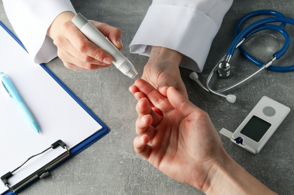 Doctor checking blood sugar level in patient diabetes on gray table