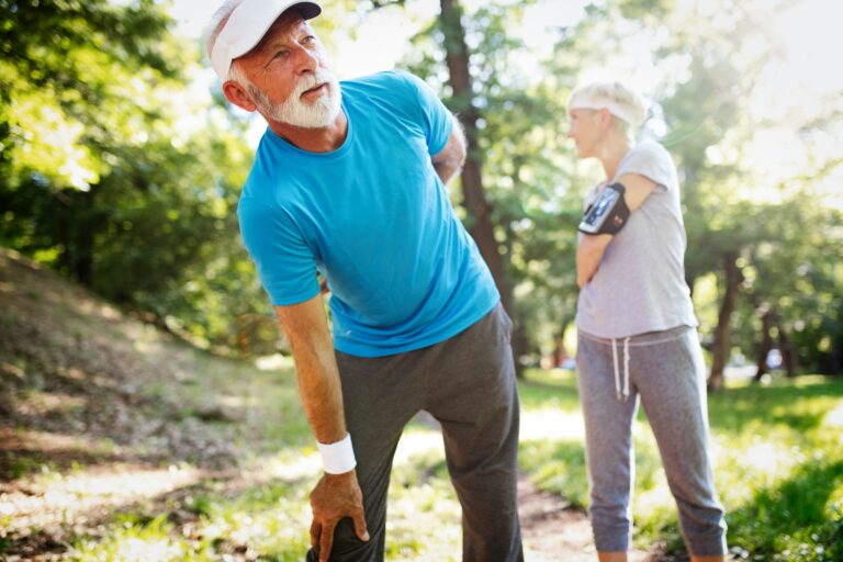 Happy mature couple stretching during running in the park